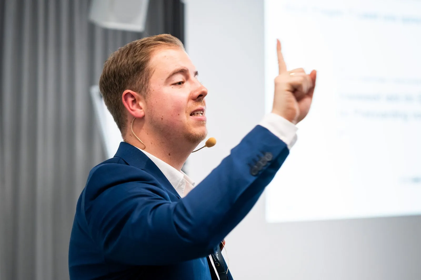 Jan Achnitz zeigt beim Deutschen Ausbildungsleiterkongress mit erhobenem Finger auf die Präsentation